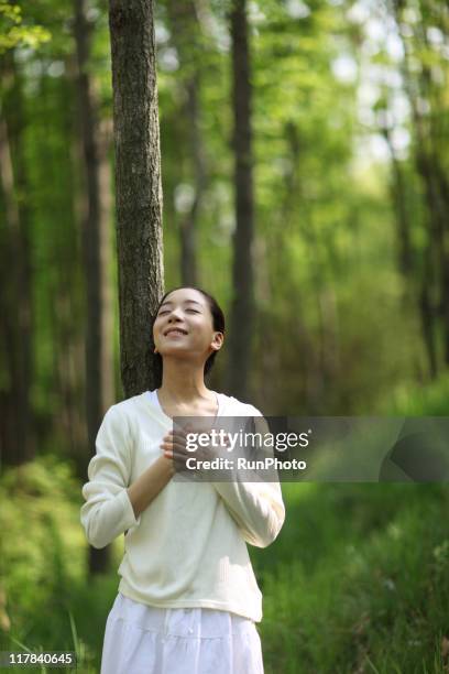 young woman takes a deep breathin the forest - main sur la poitrine photos et images de collection