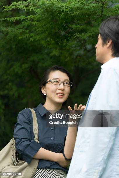 japanese woman speaking to coworker outside in kyoto japan - two international finance center stock pictures, royalty-free photos & images