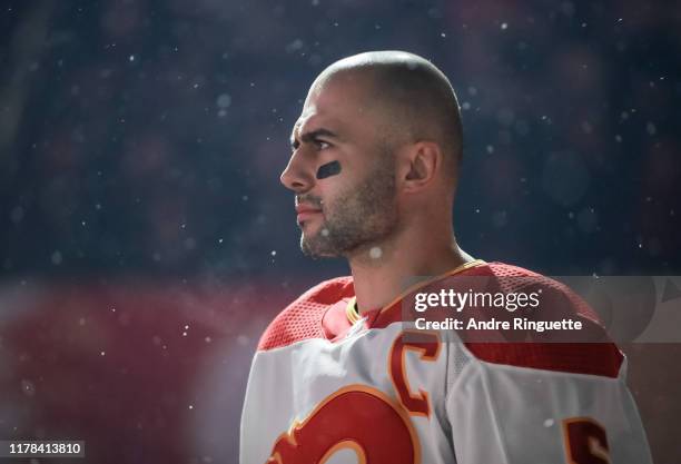 Mark Giordano of the Calgary Flames listens to the Canadian national anthem before taking on the Winnipeg Jets during the 2019 Tim Hortons NHL...