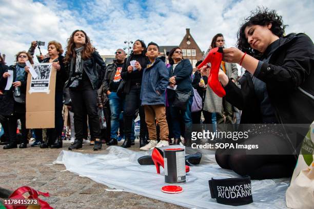 Woman is seen painting some shoes with red paint as a representation of the female victims during the demonstration. The Chilean community living in...