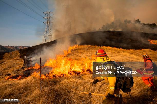 Back fire set by fire fighters burns a hillside near PG&E power lines during firefighting operations to battle the Kincade Fire in Healdsburg,...