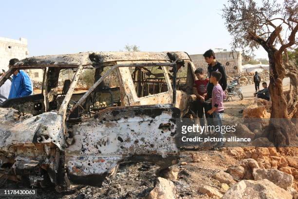 Dpatop - 27 October 2019, Syria, Barisha: Syrian children inspect a burnt vehicle at the site near the northwestern Syrian village of Barisha in the...