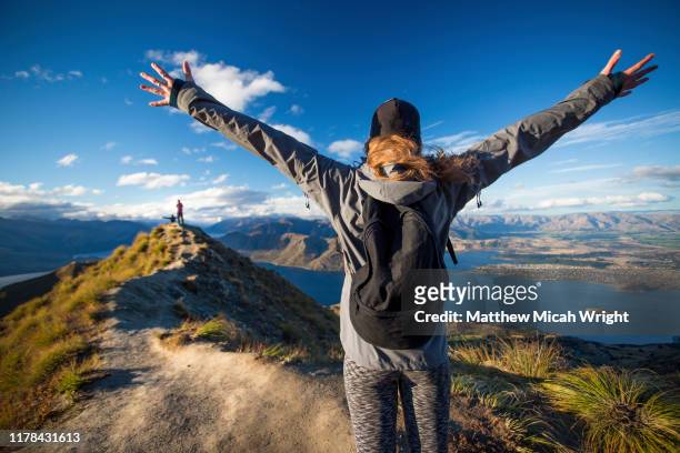 a woman walks down the trail on the roy's peak hike. - otago stockfoto's en -beelden