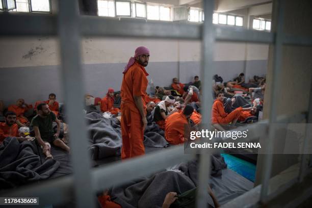 Men, accused of being affiliated with the Islamic State group, sit on the floor in a prison in the northeastern Syrian city of Hasakeh on October 26,...