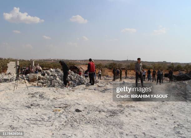 Syrians gather amidst the rubble of a building at the site of helicopter gunfire which reportedly killed nine people near the northwestern Syrian...