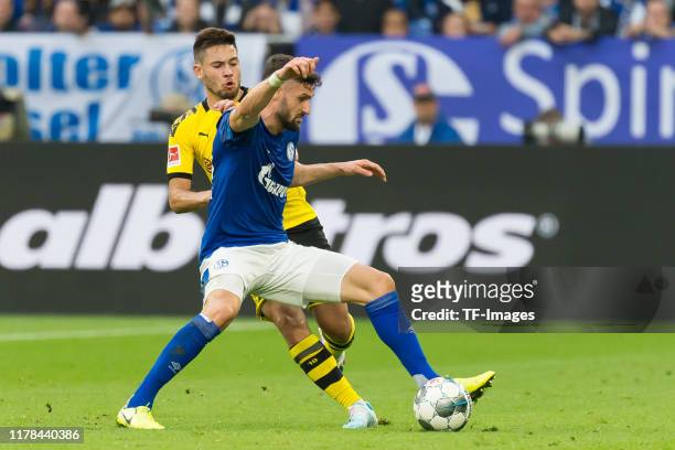 Raphael Guerreiro of Borussia Dortmund and Daniel Caligiuri of FC Schalke 04 battle for the ball during the Bundesliga match between FC Schalke 04...