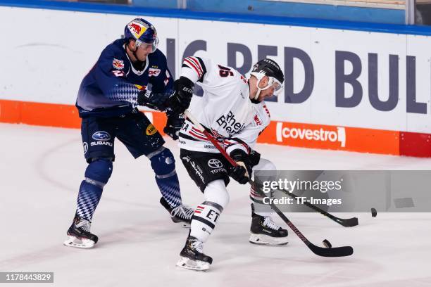 Robert Sanguinetti of EHC Red Bull Muenchen and Fabio Pfohl of Koelner Haie battle for the puck during the DEL match between EHC Red Bull Muenchen...