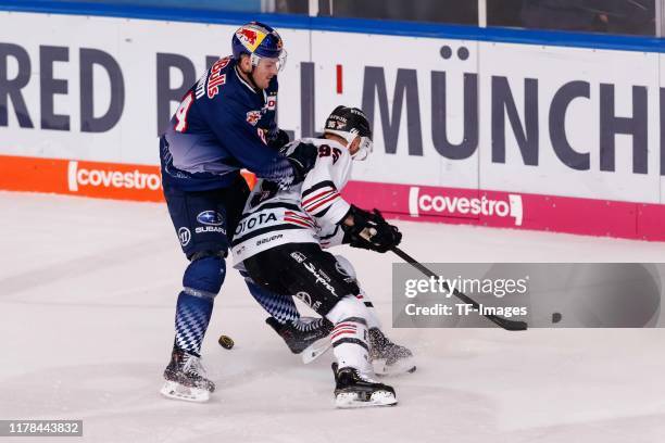 Robert Sanguinetti of EHC Red Bull Muenchen and Fabio Pfohl of Koelner Haie battle for the puck during the DEL match between EHC Red Bull Muenchen...