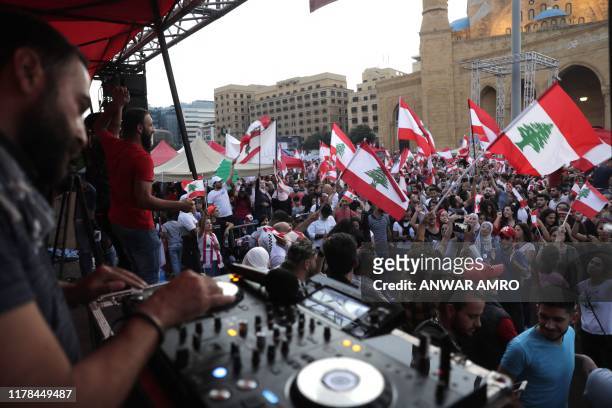 Lebanese DJ plays music as demonstrators wave national flags at the Martyrs' Square in the centre of the capital Beirut on October 27 during ongoing...