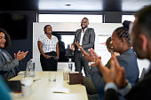Attractive black businessman being encouraged by diverse multi-ethnic group of coworkers during presentation in office