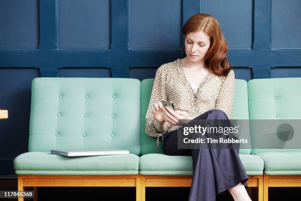 woman using smart phone on sofa. - benen over elkaar geslagen stockfoto's en -beelden