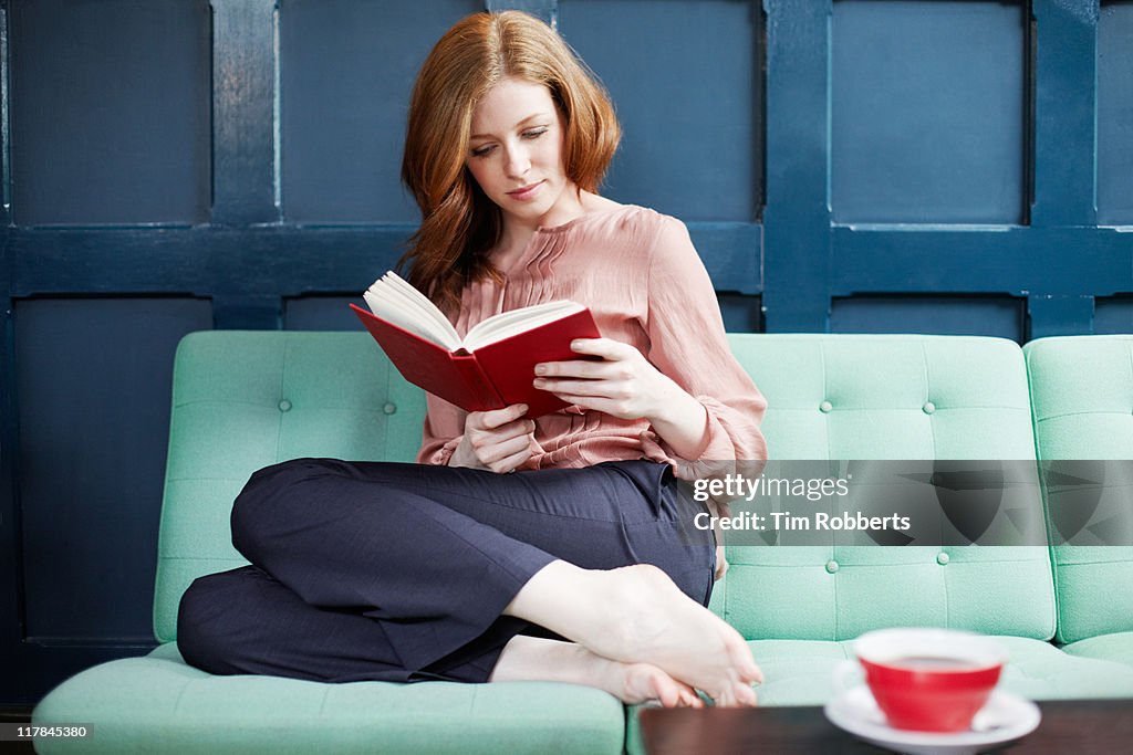 Woman reading a book on sofa.