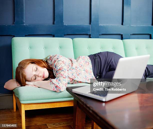 woman asleep on sofa with laptop - treuzelen stockfoto's en -beelden