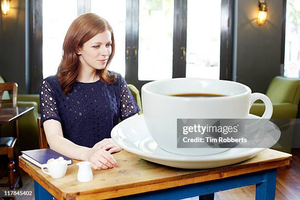 woman in coffee shop with huge coffee. - excess stock-fotos und bilder