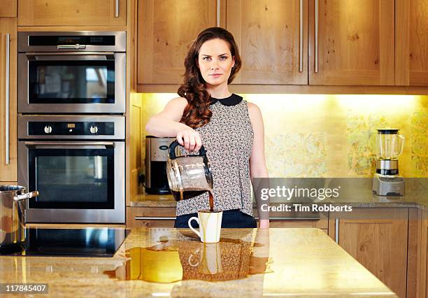 woman poring coffee into cup and over work-surface - extra portraits stockfoto's en -beelden