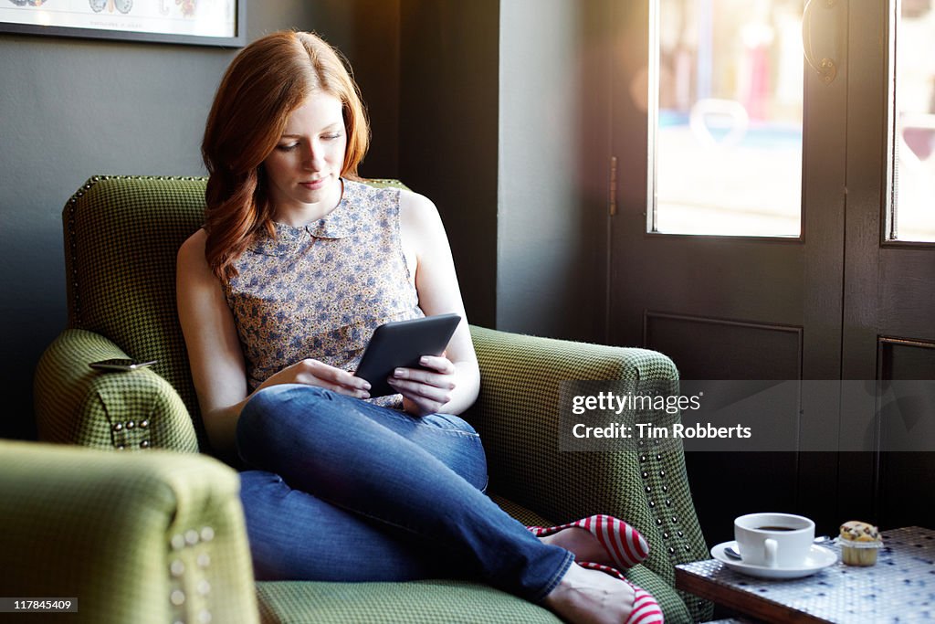 Woman reading ebook on tablet in coffee shop