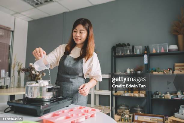 een aziatische chinese vrouwelijke ambagende persoon gieten water in de pot voor zelfgemaakte zeep maken - zeep stockfoto's en -beelden