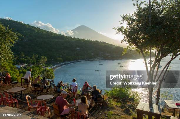 People watching the sunset behind Mount Agung from Amed sunset point in East Bali, Indonesia.