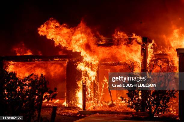 Flames consume a home during the Kincade fire as flames race through Healdsburg, California on October 27, 2019. - Powerful winds were fanning...