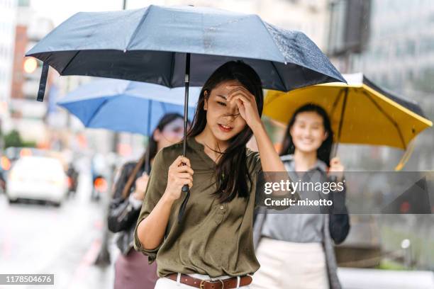 women walking with umbrella on rainy day - rainy season stock pictures, royalty-free photos & images