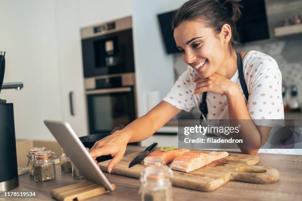 online recipe - young woman cooking in kitchen stock pictures, royalty-free photos & images