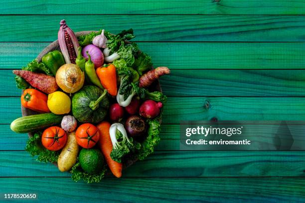 fresh organic vegetables in a round circular metal tray sitting on an old turquoise colored wood paneled table background, shot directly above with natural light, with good copy space at the right of the image. - fruit loops stock pictures, royalty-free photos & images