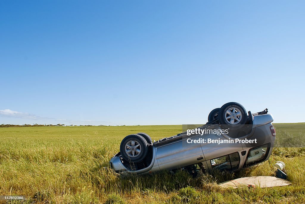 Car crashed on country road with field and sky