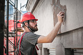 Man worker standing on scaffolding and restore old building facade