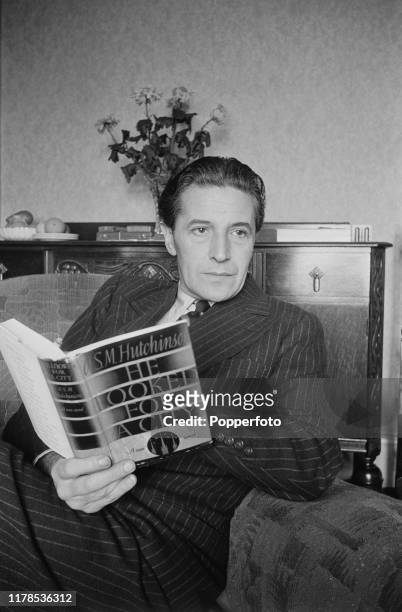Welsh composer and actor Ivor Novello seated in his rooms when staying in Blackpool, England during World War II in November 1940. Novello is reading...