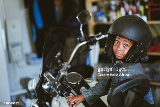 Boy wearing open face helmet sitting on motorcycle
