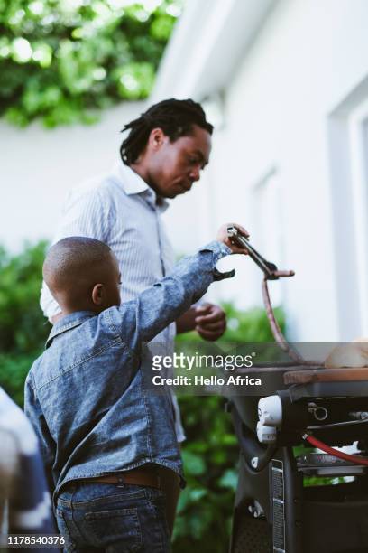 Young boy learning to barbecue with his dad side view
