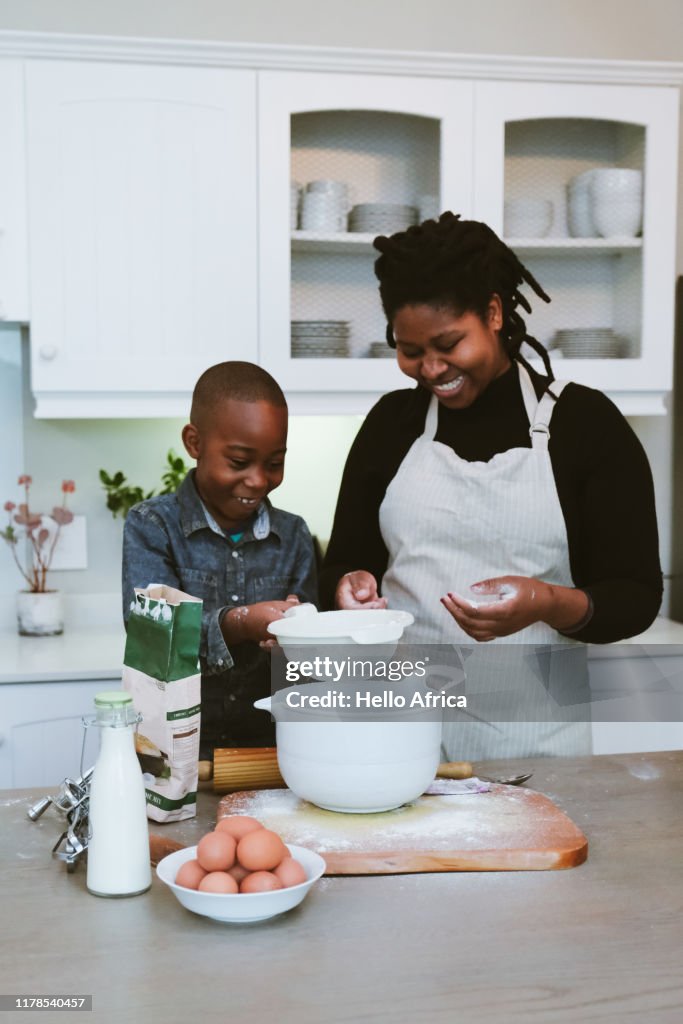 Mother teaches son how to mix dough