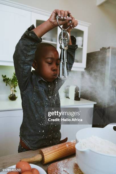 boy blowing flower off a mechanical hand-crank mixer - messy kitchen stock-fotos und bilder