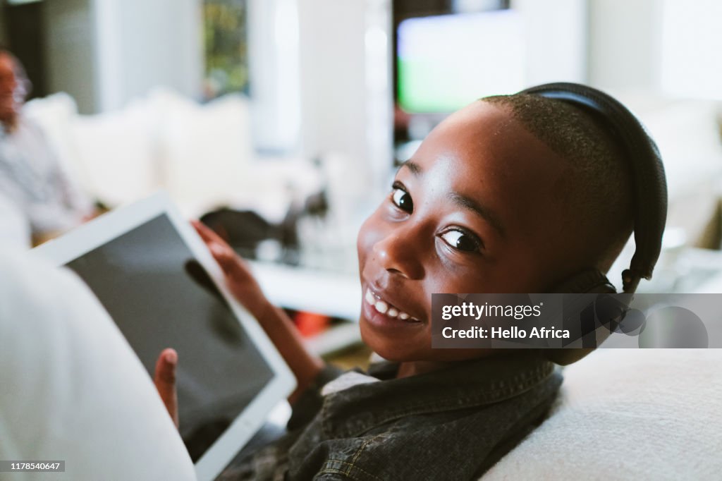 Happy boy taking a break watching a portable tablet with earphones