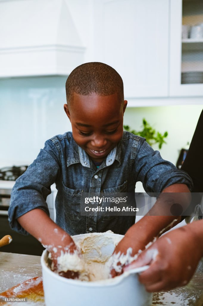 Happy boy with hands in the dough bowl