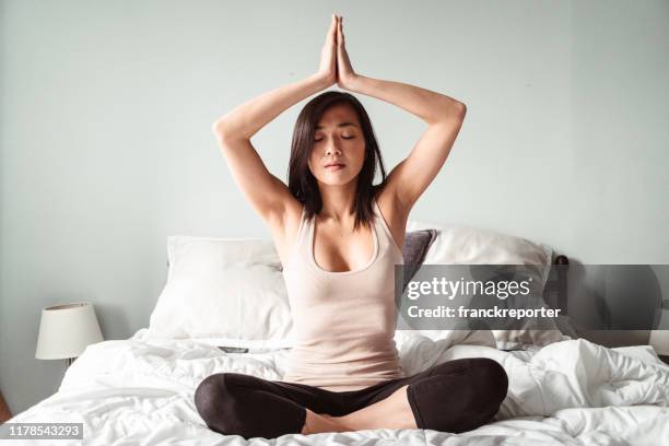 chinesische frau macht yoga im bett - daily sport girls stock-fotos und bilder