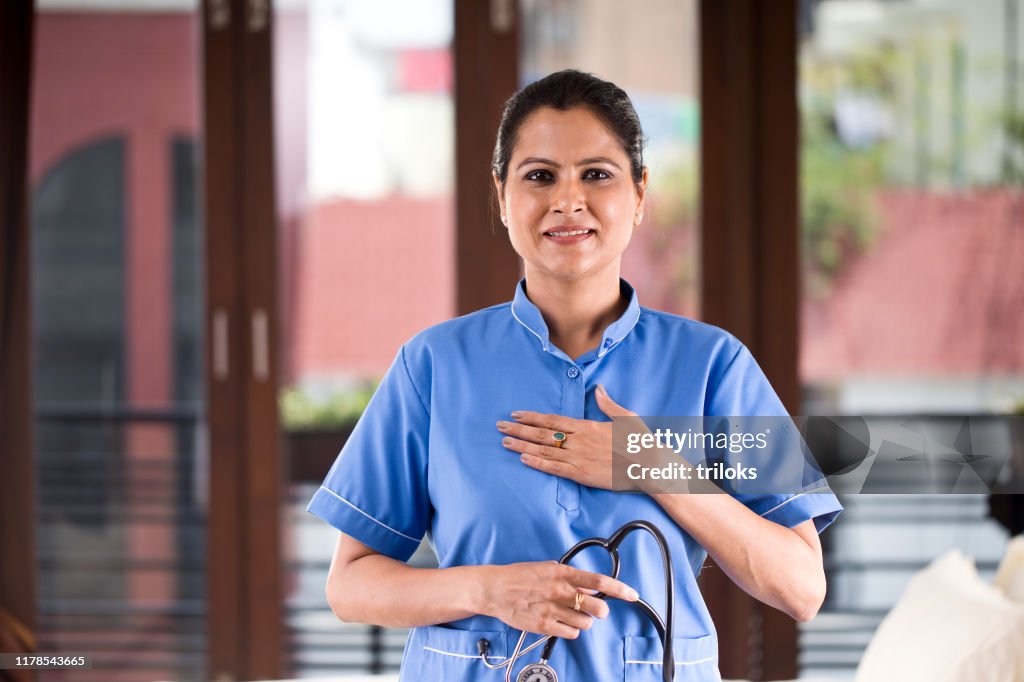 Positive female nurse with hands on chest at hospital