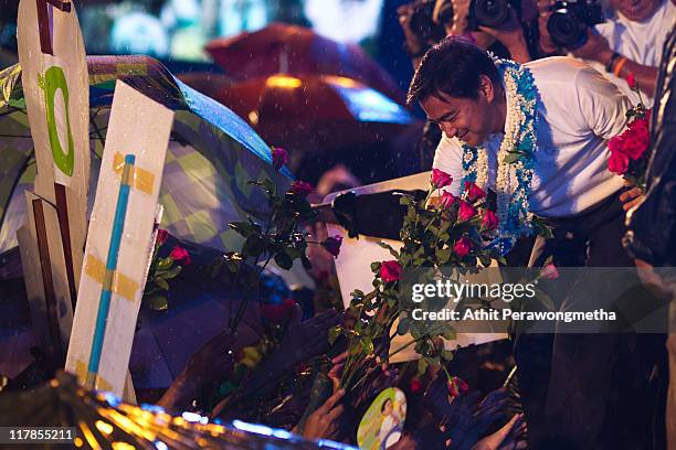 Thai Prime Minister and leader of the Democrat party Abhisit Vejjajiva receives flowers during a final campaign rally under heavy rain at Royal Plaza...