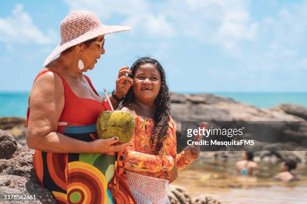 grandma enjoying the tropical beach with her granddaughter - coconut beach woman stock pictures, royalty-free photos & images