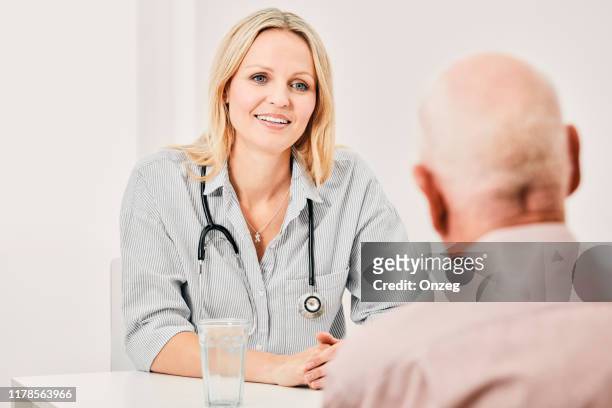 general physician discussing with elderly patient - general practitioner imagens e fotografias de stock
