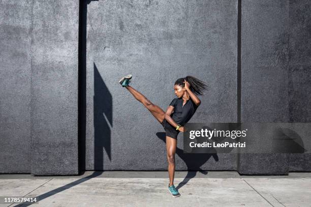 afro amerikanische frau mit dreadlocks in einer großen sportlichen form trainieren und training hart im freien - kicking stock-fotos und bilder