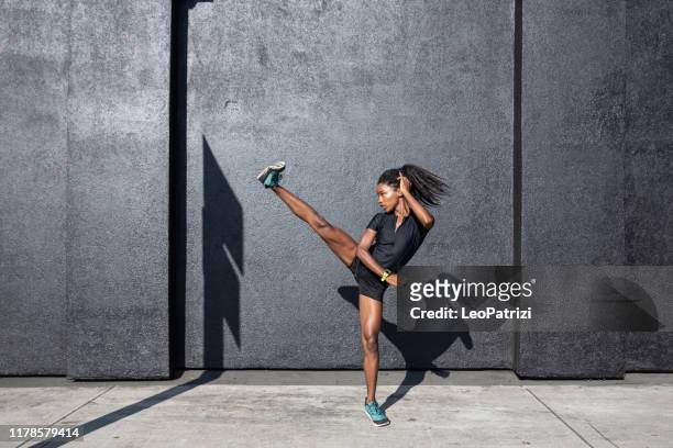 donna afro-americana con dreadlocks in grande forma atletica che si allena e si allena duramente all'aperto - calciare foto e immagini stock