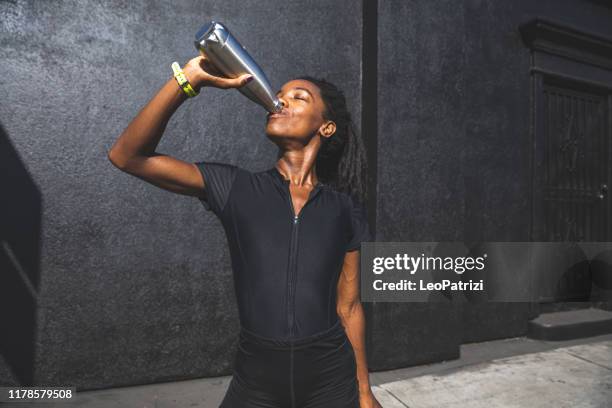 afro american woman with dreadlocks in a great athletic shape working out and training hard outdoors - energy drink stock pictures, royalty-free photos & images