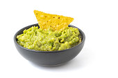 Green Guacamole with nachos in dark bowl isolated on white background