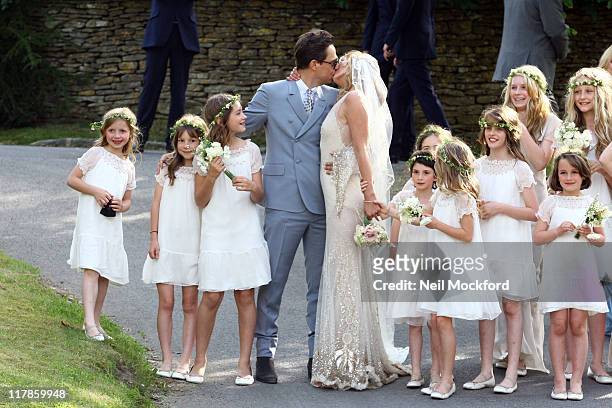 Jamie Hince kisses his new bride Kate Moss as their bridesmaids look on outside the church after their wedding on July 1, 2011 in Southrop, England.