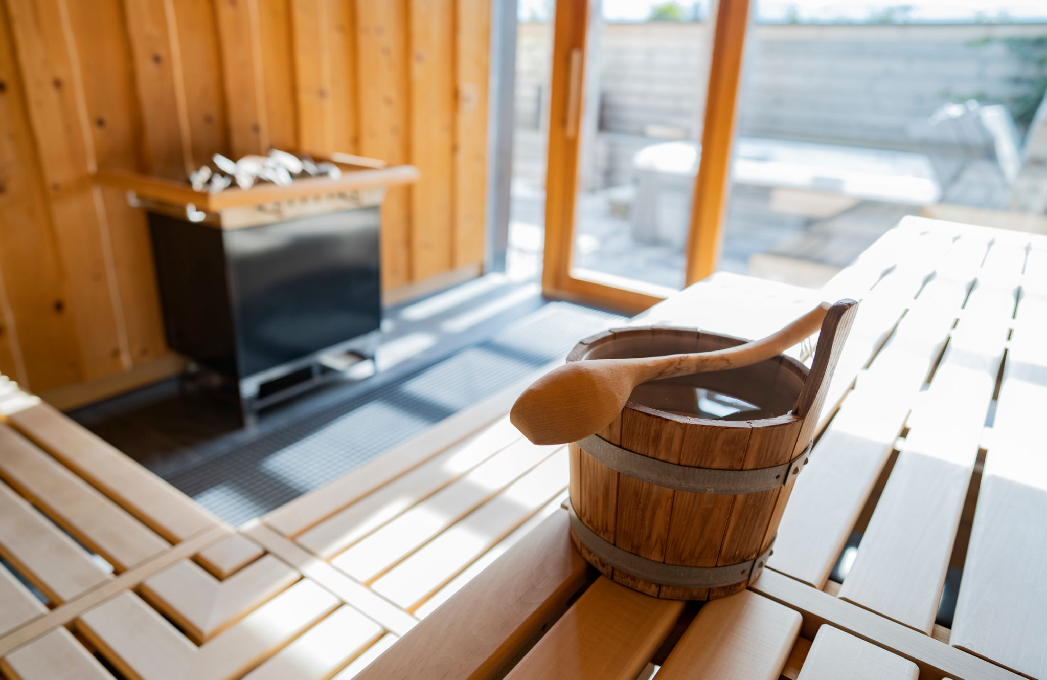 indoor of a Finnish sauna, with a water bucket and sunlight shining through a big window, Spa and Wellness concept in a hotel indoor of a Finnish sauna, with a water bucket and sunlight shining through a big window, Spa and Wellness concept in a hotel