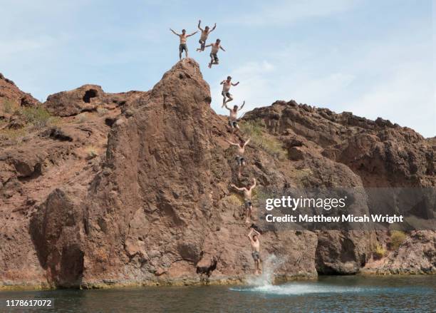 a man jumps off a cliff in copper canyon, lake havasu. - lake havasu stock pictures, royalty-free photos & images