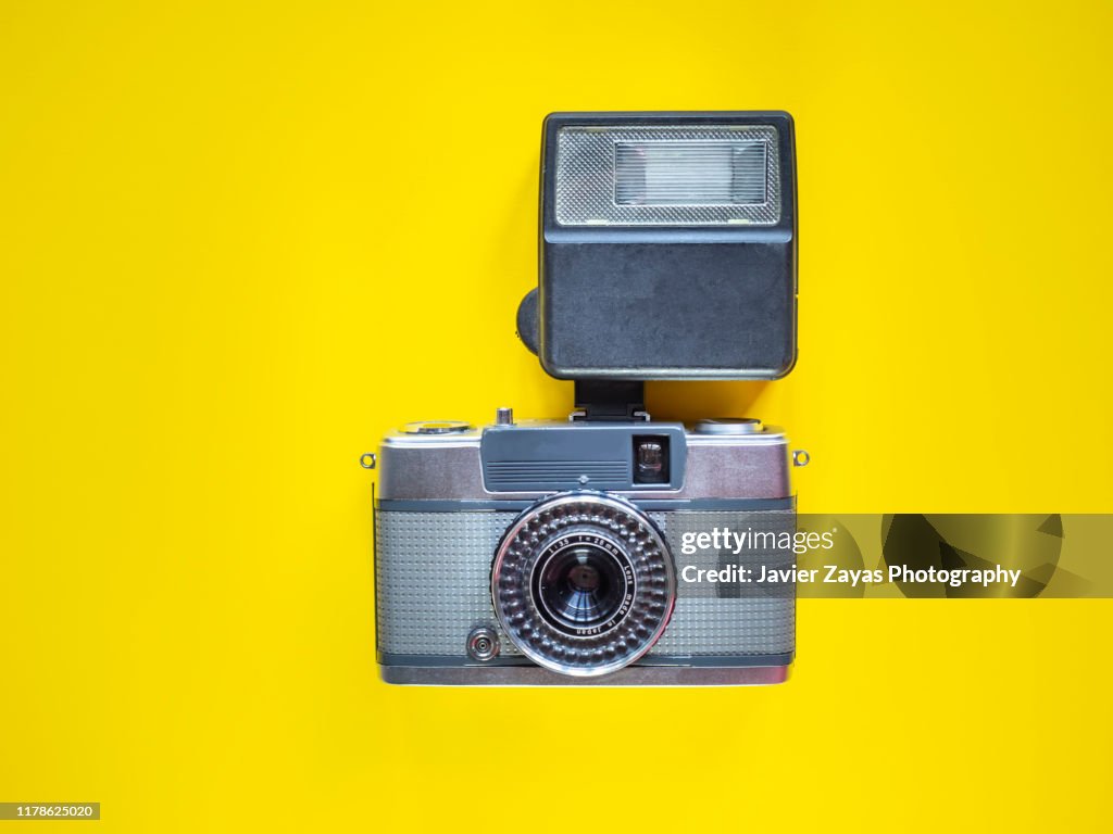 Directly Above View Of Retro Vintage Camera And Speedflash On Yellow Background