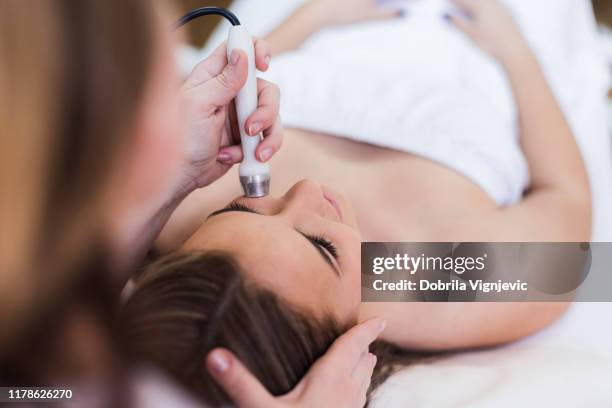 young woman get face treatments at beauty clinic - beauty therapy stock pictures, royalty-free photos & images