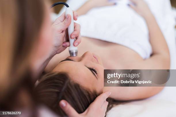 年輕女子在美容診所接受面部護理 - lazer 個照片及圖片檔